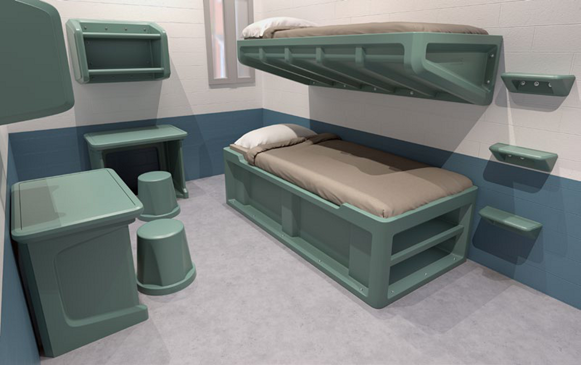 Custodial cell fitted with an anti-ligature bunk, wall-mounted desk and moulded stools